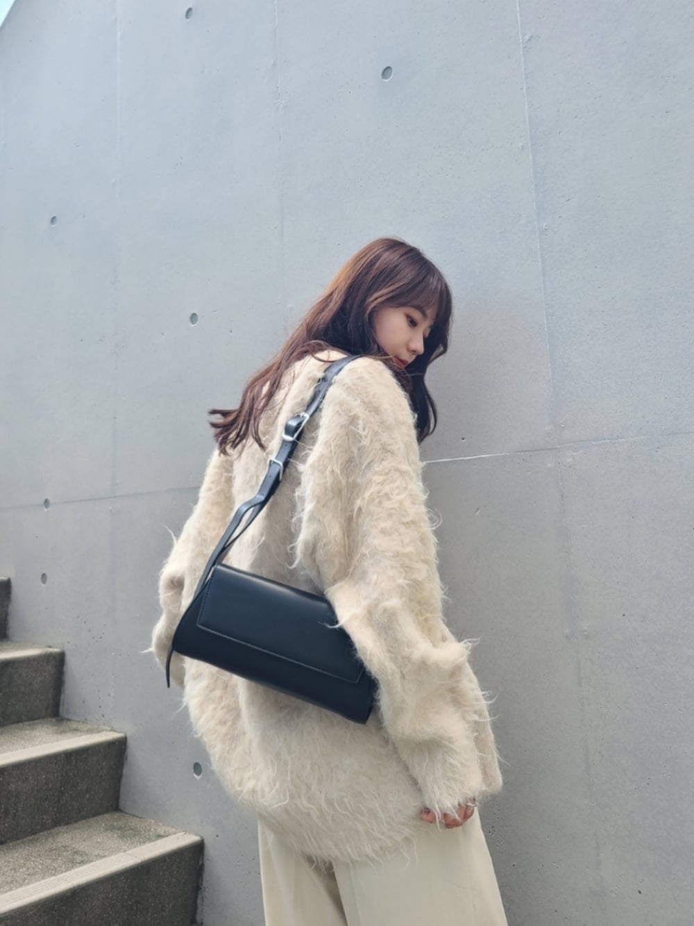 ホワイト系のパンツ、ホワイト系のカーディガン/ボレロ、ブラック系のショルダーバッグを着用したレディースの秋コーディネートの2枚目の写真