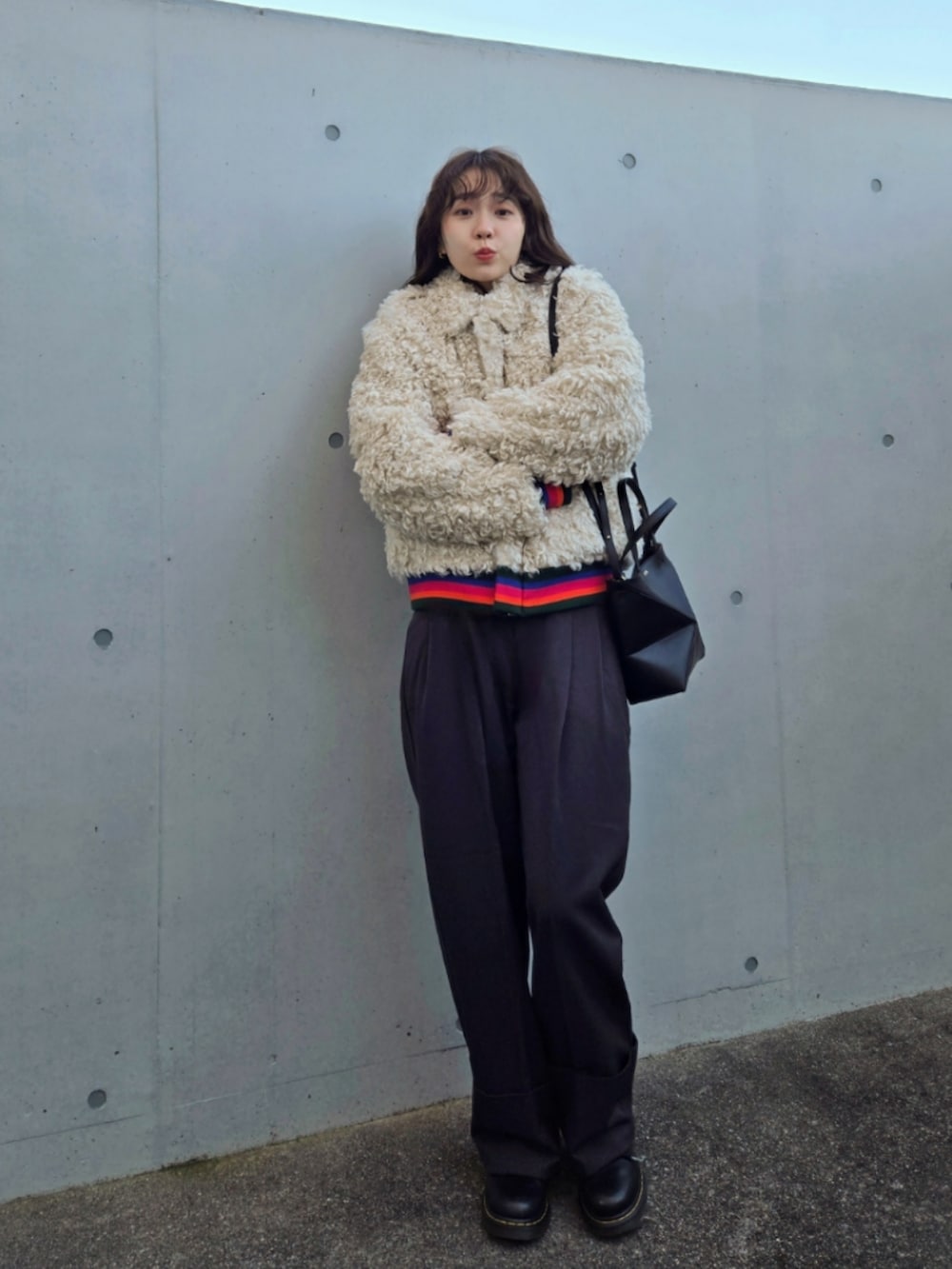 ベージュ系のブルゾン、ブラック系のトートバッグ、グレー系のスラックスを着用したレディースの冬コーディネートの3枚目の写真