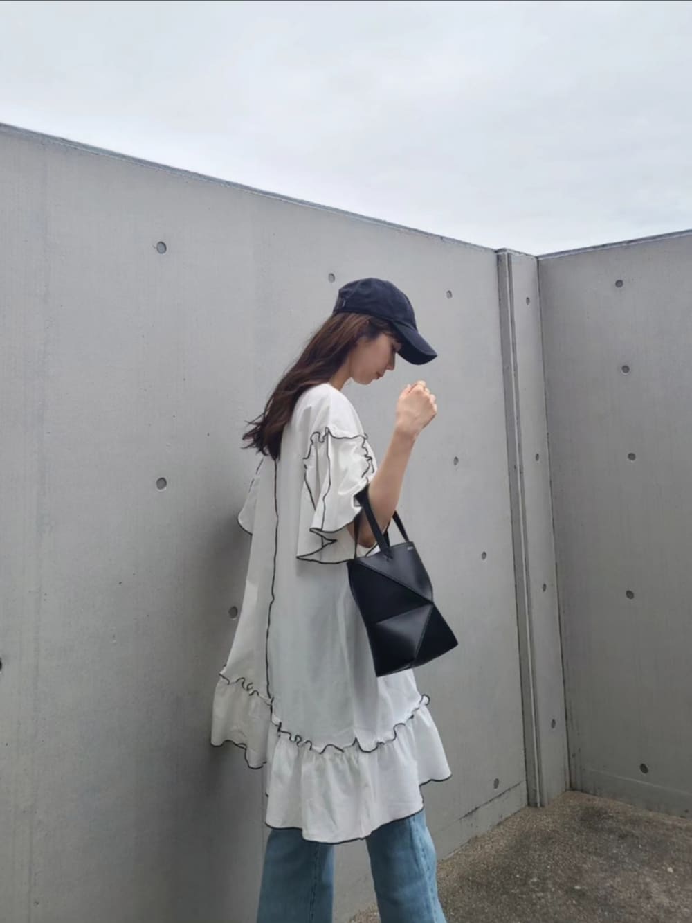 ブラック系のトートバッグ、ブルー系のデニムパンツ、ホワイト系のサンダルを着用したレディースの春コーディネートの2枚目の写真