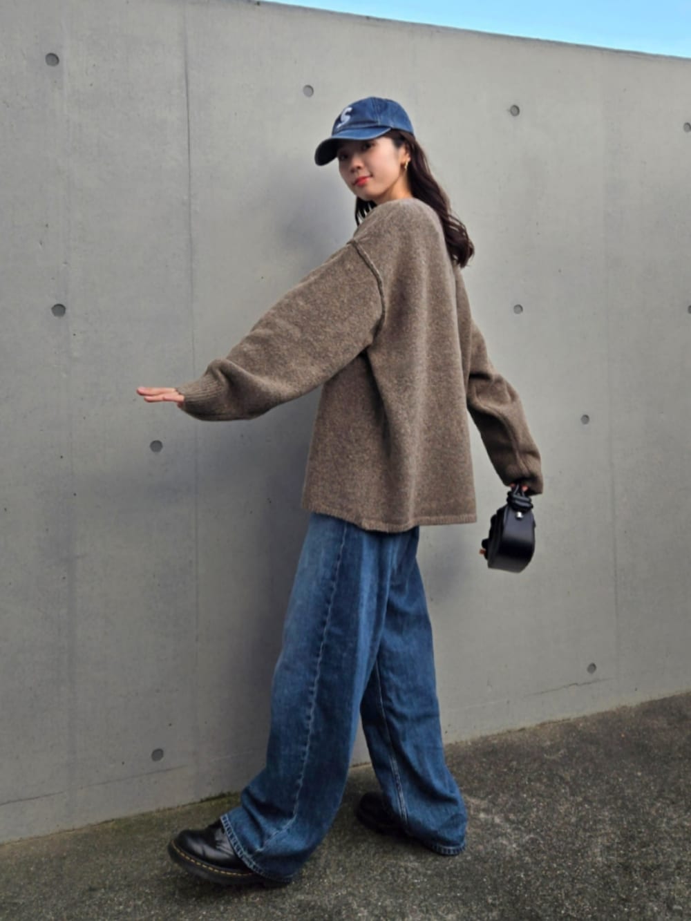 ブルー系のデニムパンツ、ブラウン系のカーディガン/ボレロ、ブラック系のハンドバッグを着用したレディースの秋コーディネートの4枚目の写真