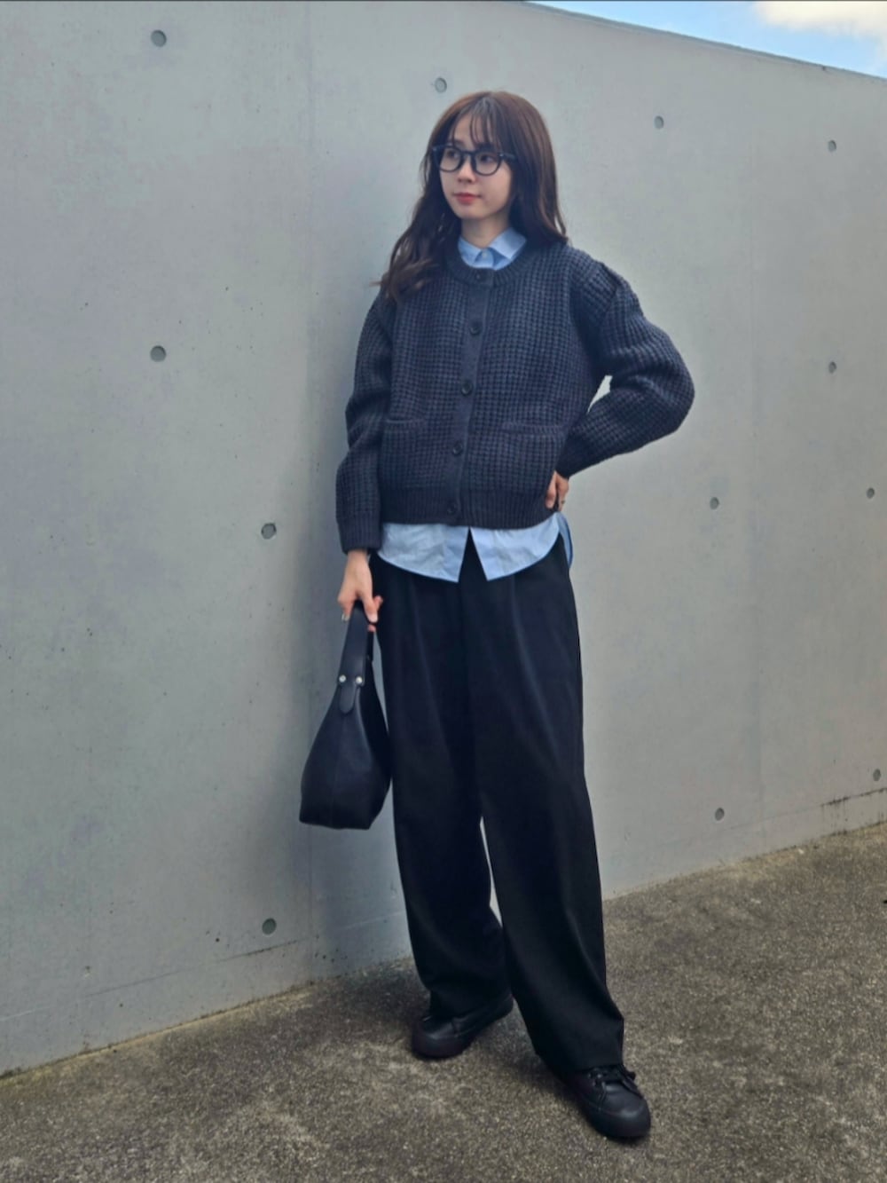 ブラック系のハンドバッグ、ブラック系のパンツ、グレー系のカーディガン/ボレロを着用したレディースの秋コーディネートの3枚目の写真