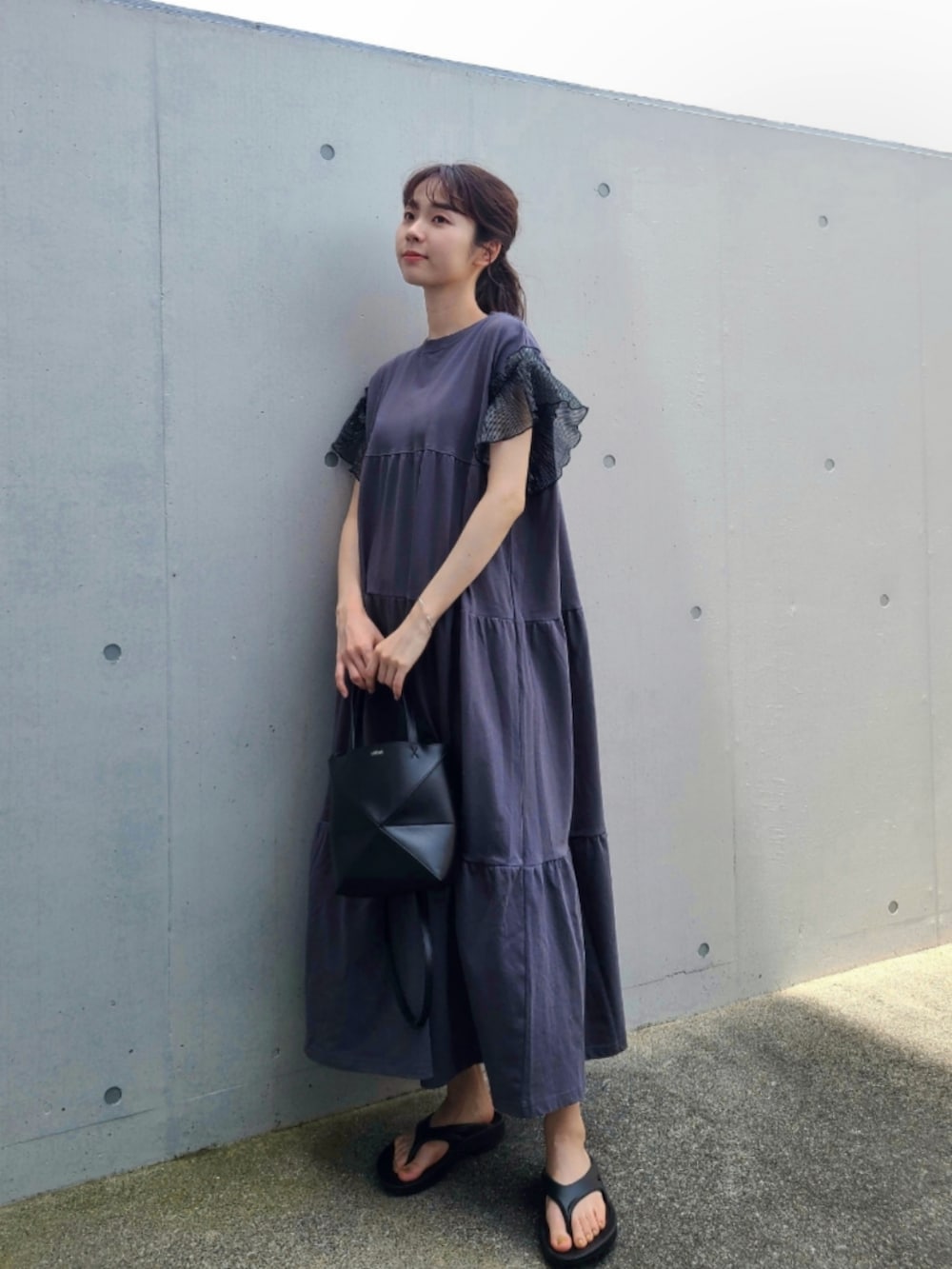 ブラック系のサンダル、ブラック系のトートバッグ、ブラック系のワンピースを着用したレディースの夏コーディネートの2枚目の写真