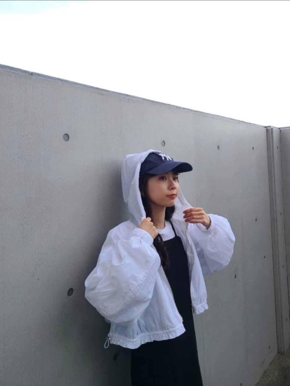 ブラック系のハンドバッグ、ホワイト系のナイロンジャケット、ブルー系のスニーカーを着用したレディースの春コーディネートの3枚目の写真