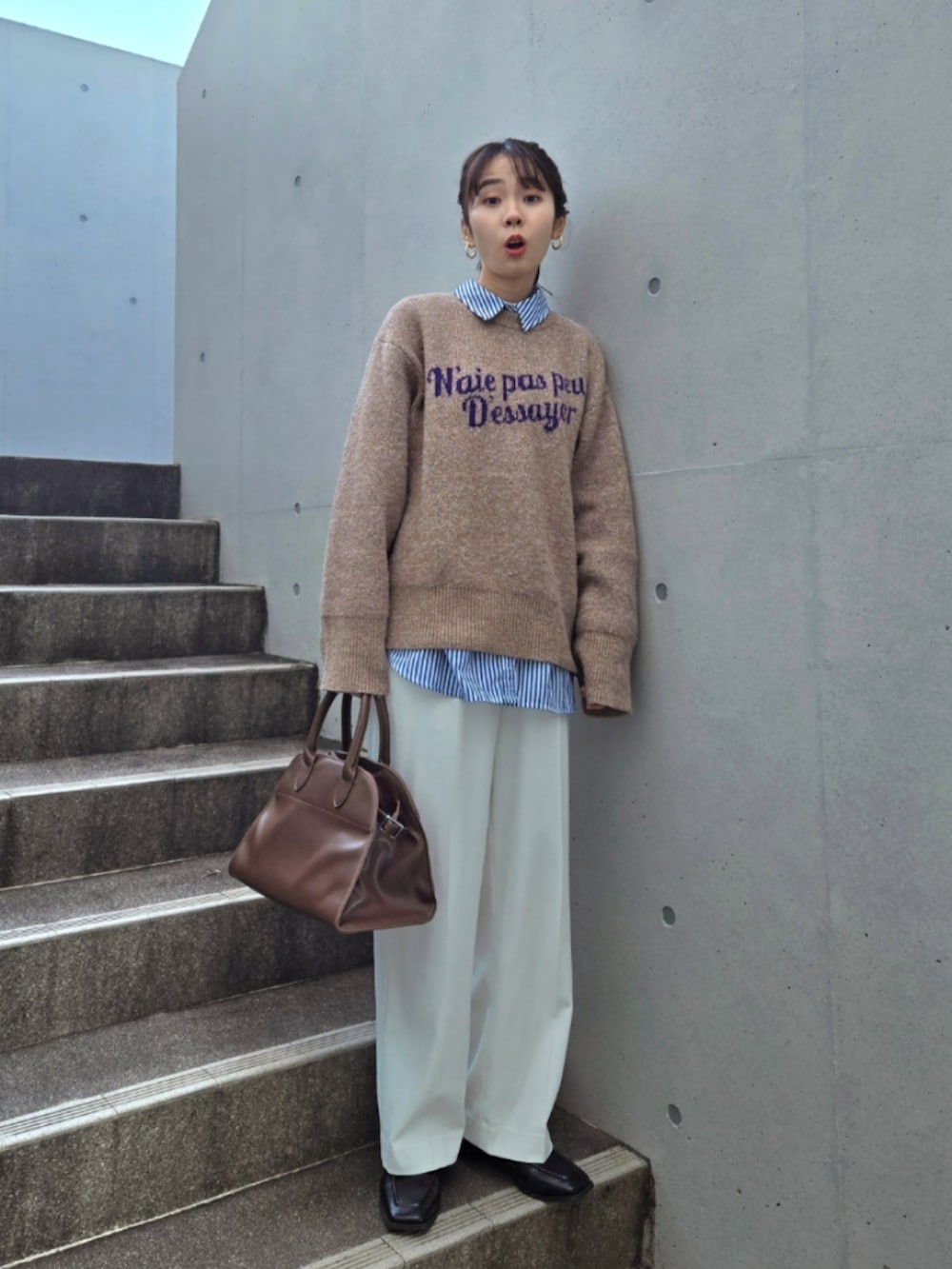 ブラウン系のニット/セーター、ブラウン系のボストンバッグ、ホワイト系のパンツを着用したレディースの冬コーディネートの2枚目の写真