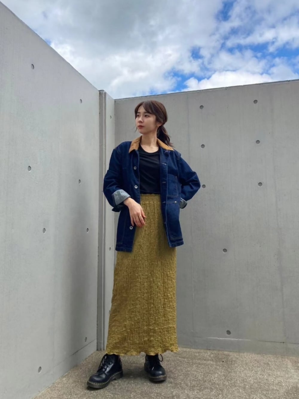 ブルー系のデニムジャケット、グリーン系のスカート、ブラック系のブーツを着用したレディースの秋コーディネートの2枚目の写真