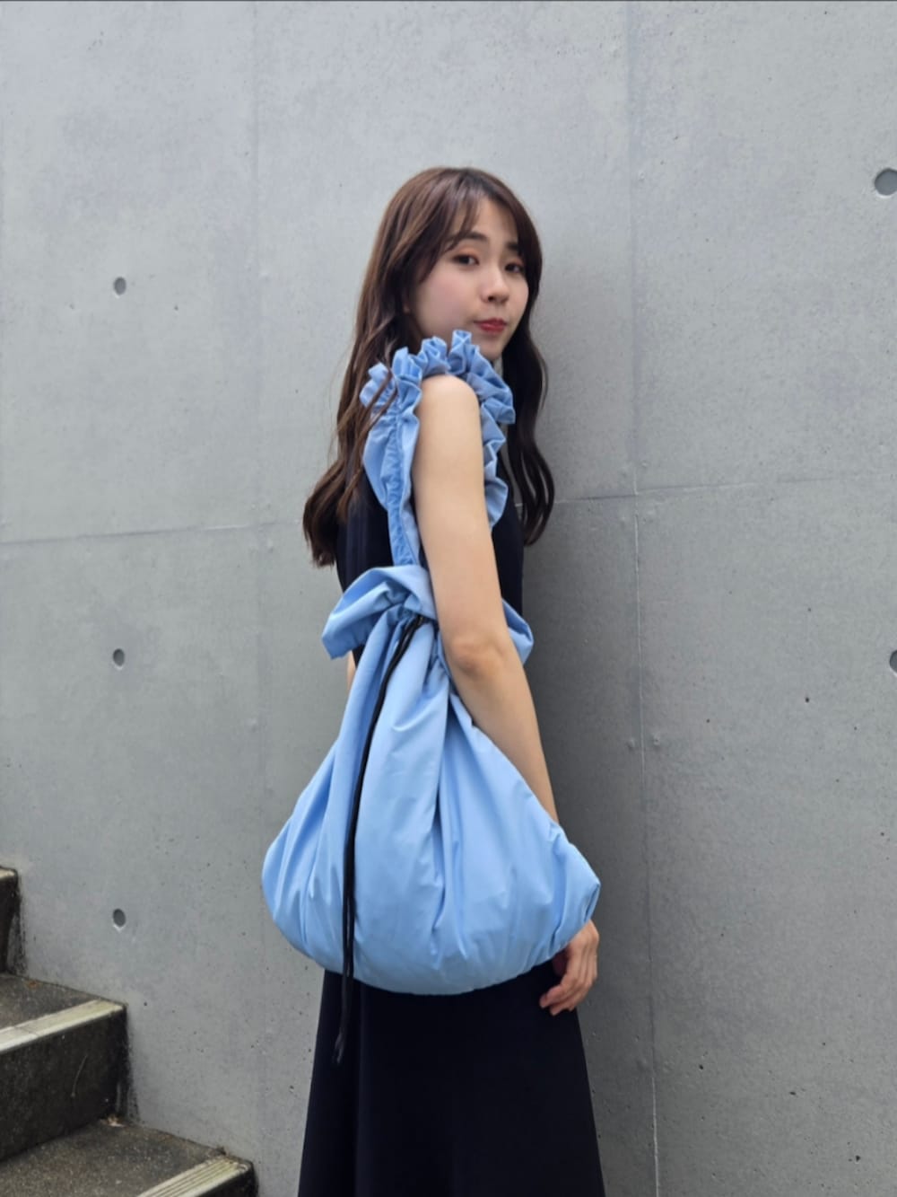 ブルー系のショルダーバッグ、ブラック系のサンダル、ブラック系のワンピースを着用したレディースの春コーディネートの3枚目の写真