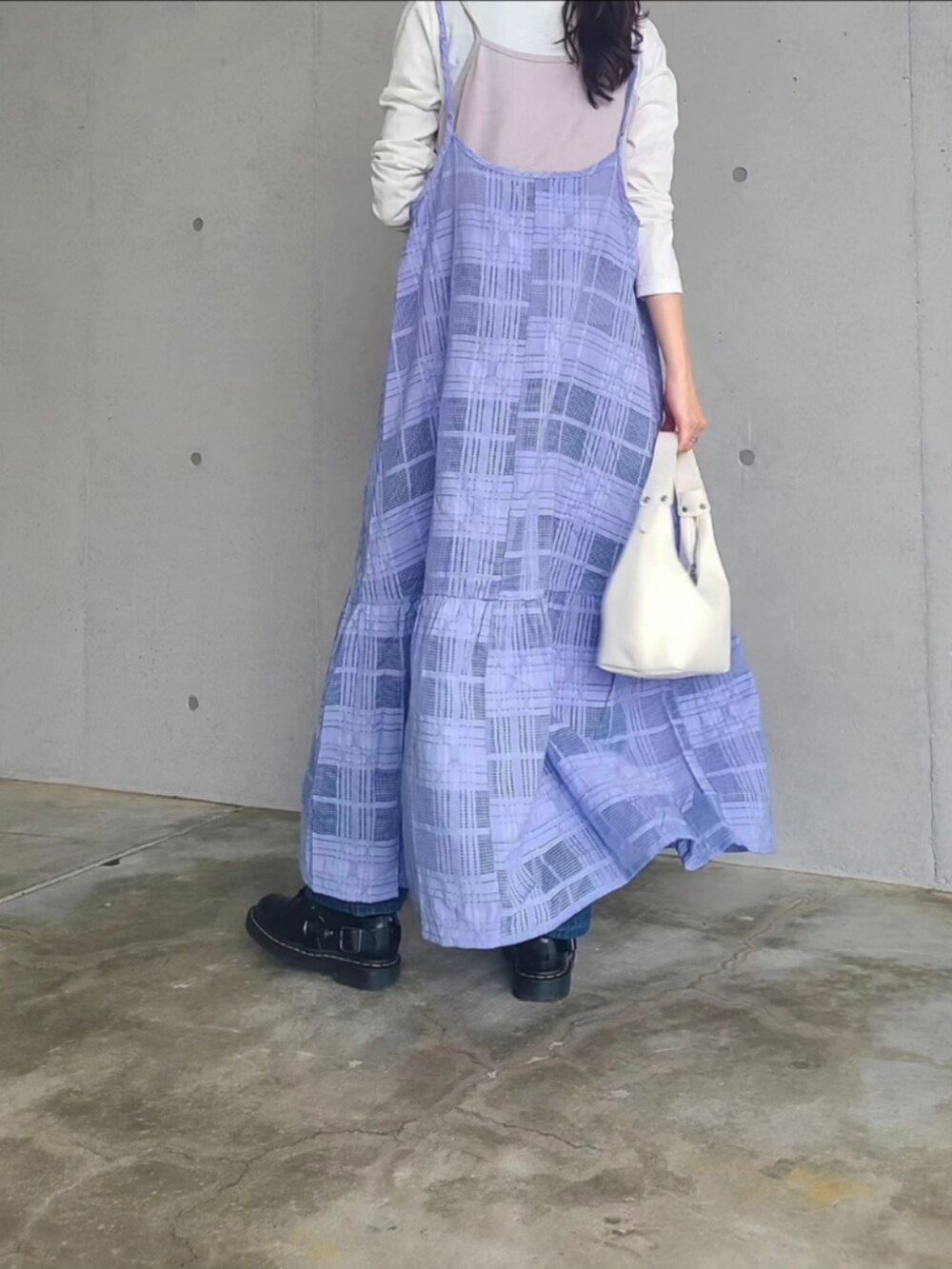 ホワイト系のハンドバッグ、ブラック系のブーツ、ブルー系のデニムパンツを着用したレディースの春コーディネートの3枚目の写真