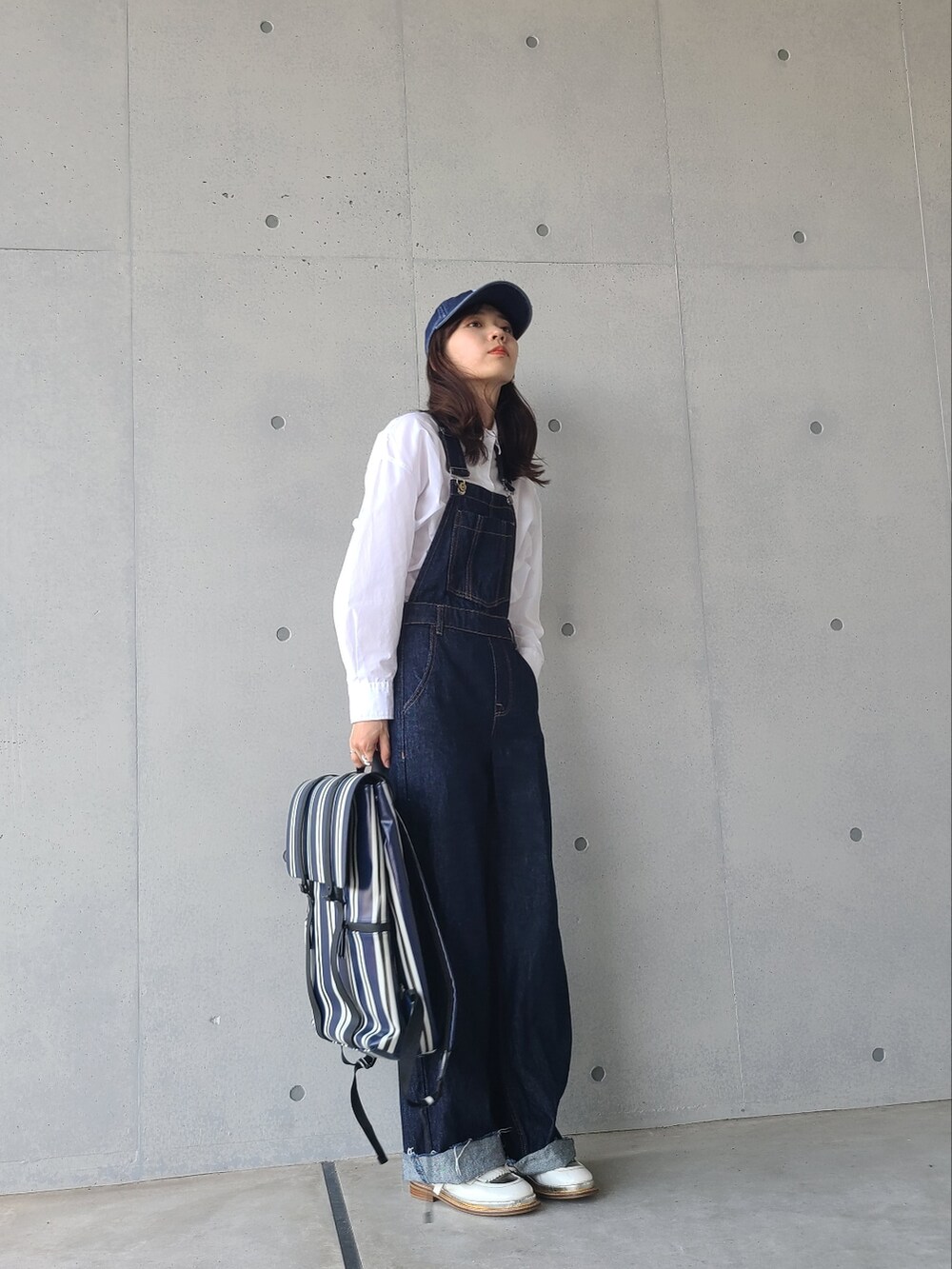 ブルー系のバックパック/リュック、ホワイト系のシャツ/ブラウス、ブルー系のサロペット/オーバーオールを着用したレディースの秋コーディネートの2枚目の写真