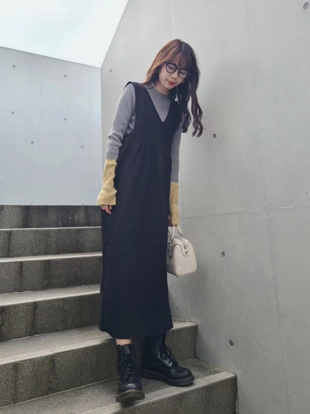 グレー系のニット/セーター、ブラック系のブーツ、ブラック系のジャンパースカートを着用したレディースの冬コーディネートの3枚目の写真