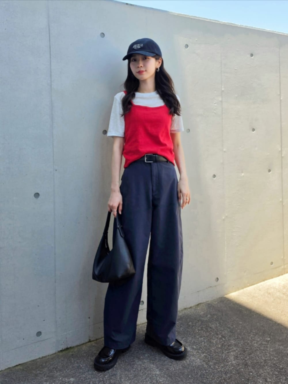 ブラック系のハンドバッグ、ブルー系のパンツ、レッド系のタンクトップを着用したレディースの春コーディネートの3枚目の写真