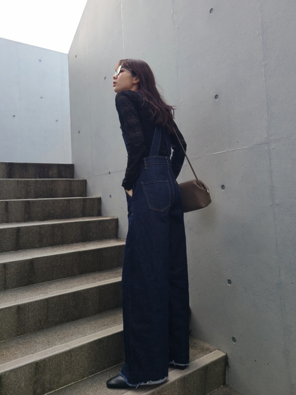 ブルー系のサロペット/オーバーオール、ブラウン系のボストンバッグ、ブラック系のブーツを着用したレディースの冬コーディネートの2枚目の写真