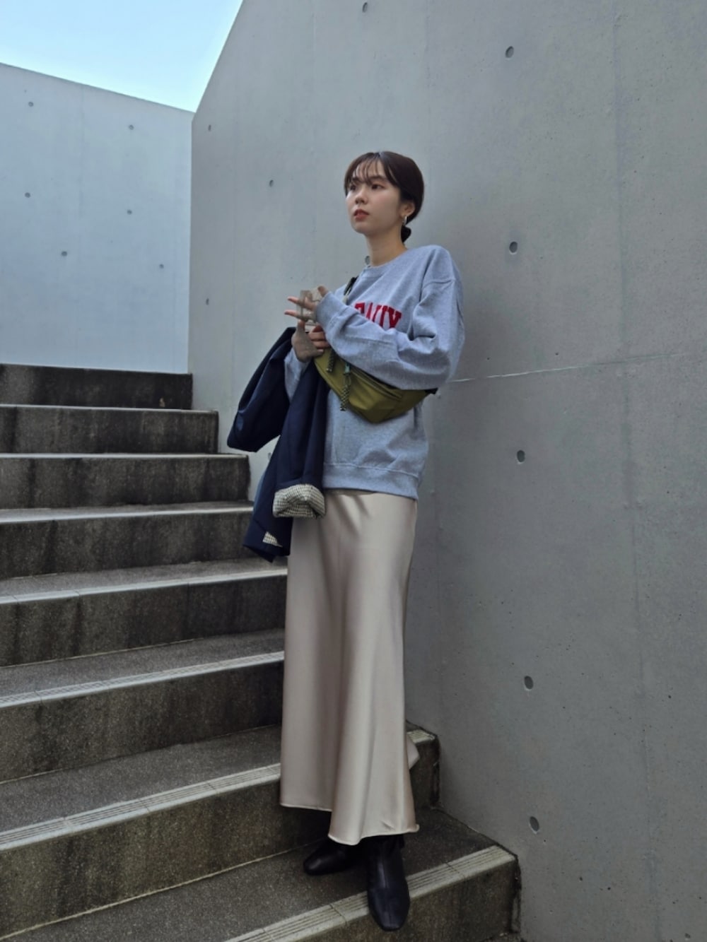 ブラック系のブーツ、ホワイト系のスカート、グリーン系のボディバッグ/ウエストポーチを着用したレディースの秋コーディネートの3枚目の写真