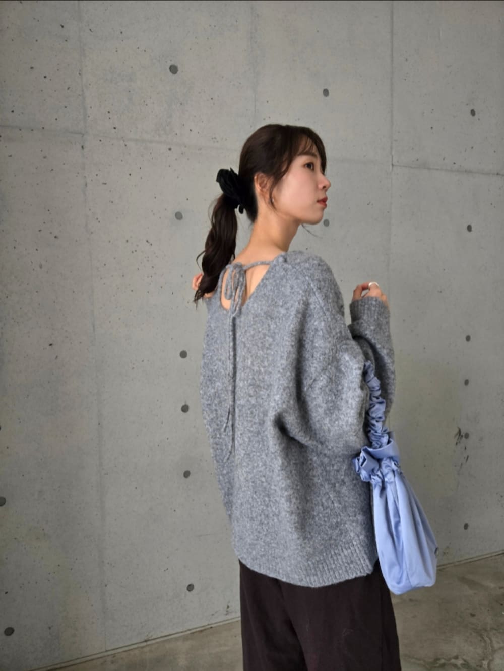 グレー系のニット/セーター、ブルー系のショルダーバッグ、ブラウン系のスウェットパンツを着用したレディースの秋コーディネートの2枚目の写真