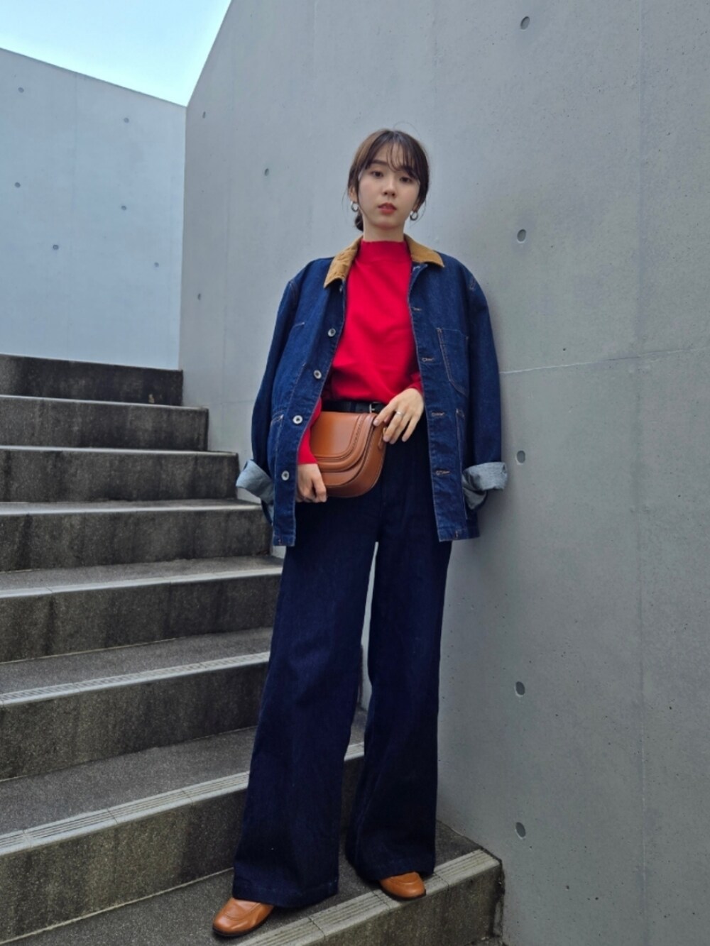 ブルー系のデニムパンツ、ブラウン系のバッグ、ブルー系のデニムジャケットを着用したレディースの秋コーディネートの3枚目の写真