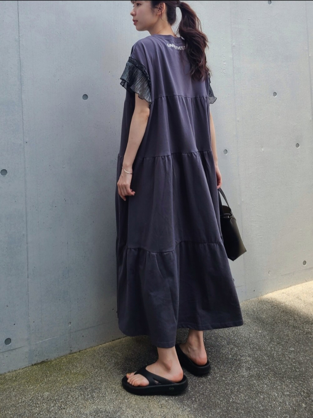 ブラック系のサンダル、ブラック系のトートバッグ、ブラック系のワンピースを着用したレディースの夏コーディネートの3枚目の写真