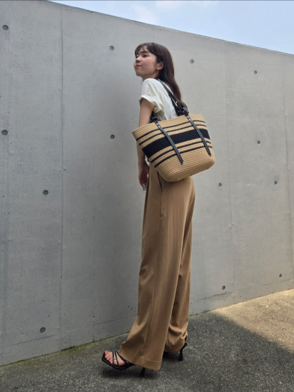 ベージュ系のかごバッグ、ベージュ系のTシャツ/カットソー、ベージュ系のパンツを着用したレディースの夏コーディネートの3枚目の写真