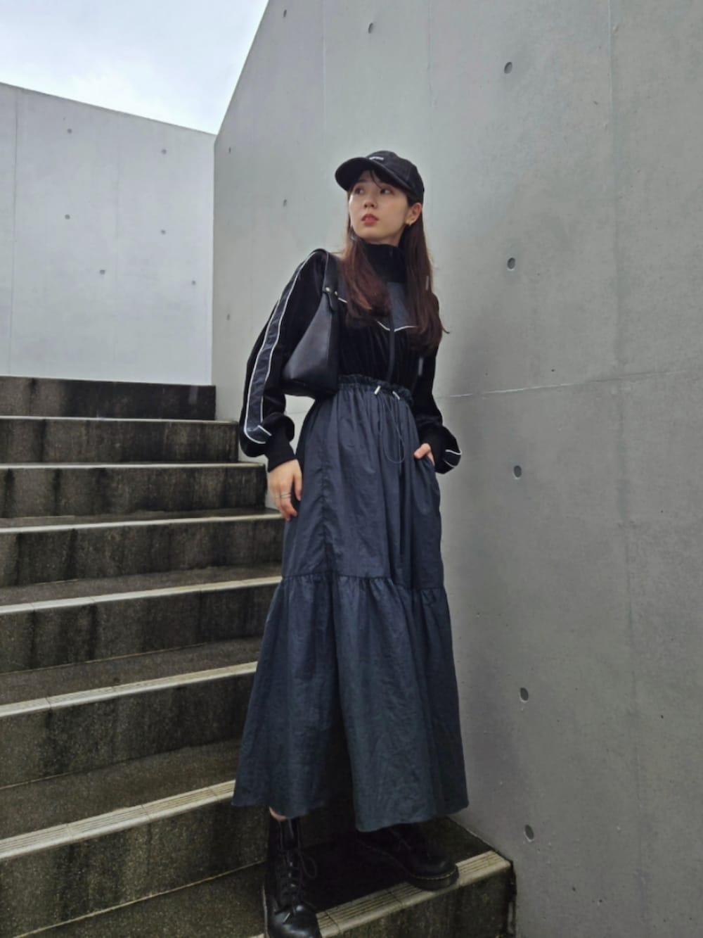 ブルー系のワンピース、ブラック系のブーツ、ブラック系のキャップを着用したレディースの秋コーディネートの3枚目の写真