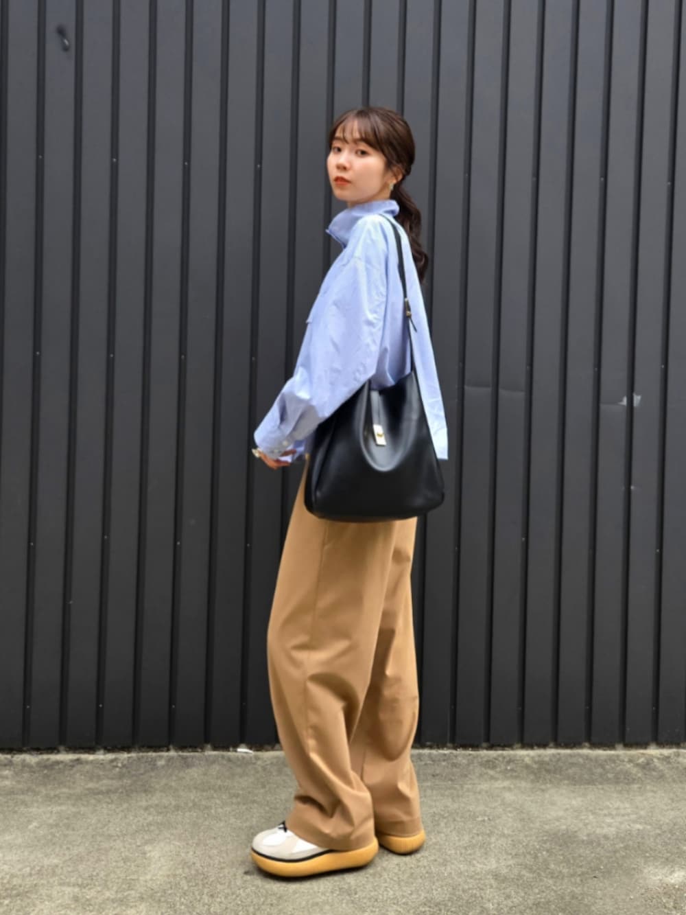 ベージュ系のパンツ、ブラック系のトートバッグ、ホワイト系のTシャツ/カットソーを着用したレディースの秋コーディネートの3枚目の写真