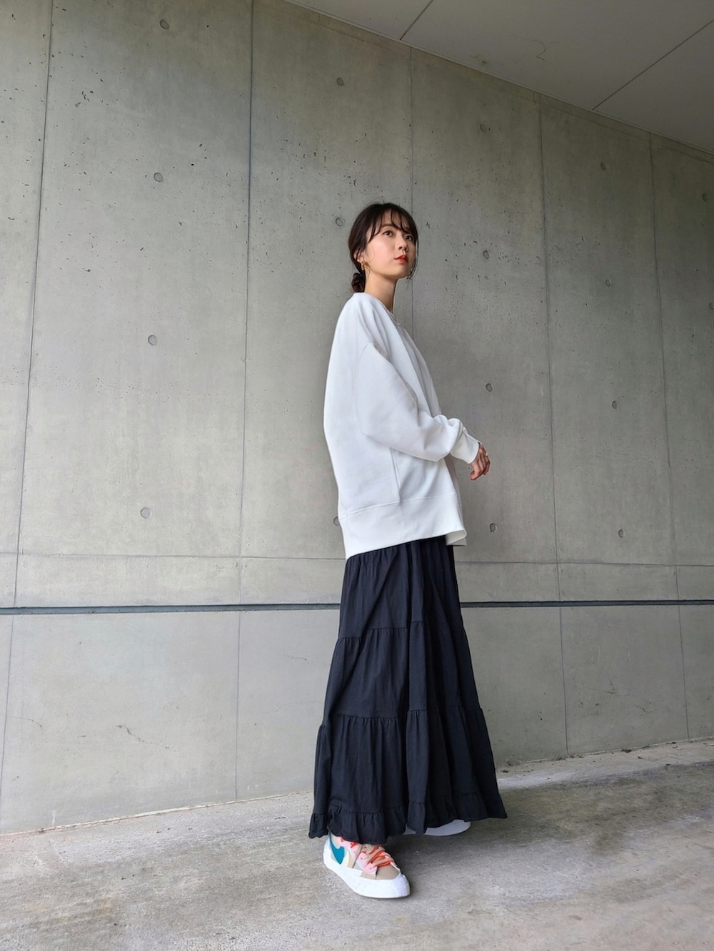 ホワイト系のスウェット、ブラック系のスカート、その他のスニーカーを着用したレディースの秋コーディネートの2枚目の写真