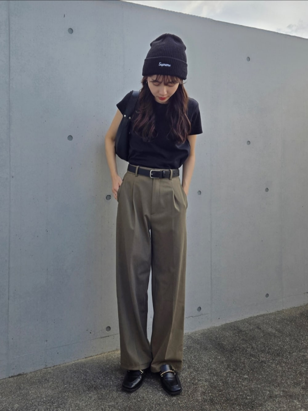 ブラック系のTシャツ/カットソー、ブラック系のハンドバッグ、グリーン系のパンツを着用したレディースの秋コーディネートの4枚目の写真
