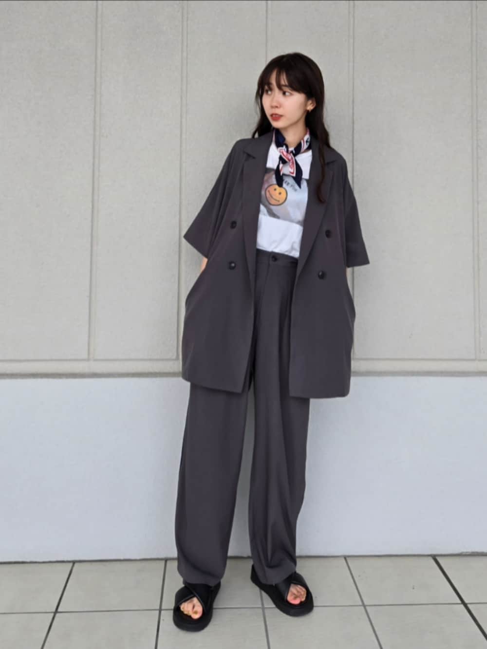 ブラック系のサンダル、ブラウン系のかごバッグ、グレー系のテーラードジャケットを着用したレディースの秋コーディネートの2枚目の写真