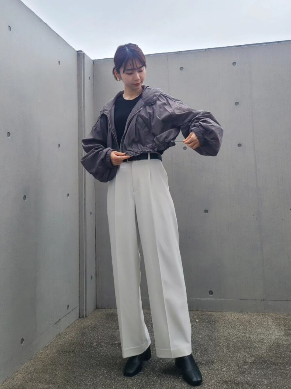 ブラック系のナイロンジャケット、ホワイト系のパンツ、ブラック系のブーツを着用したレディースの春コーディネートの4枚目の写真