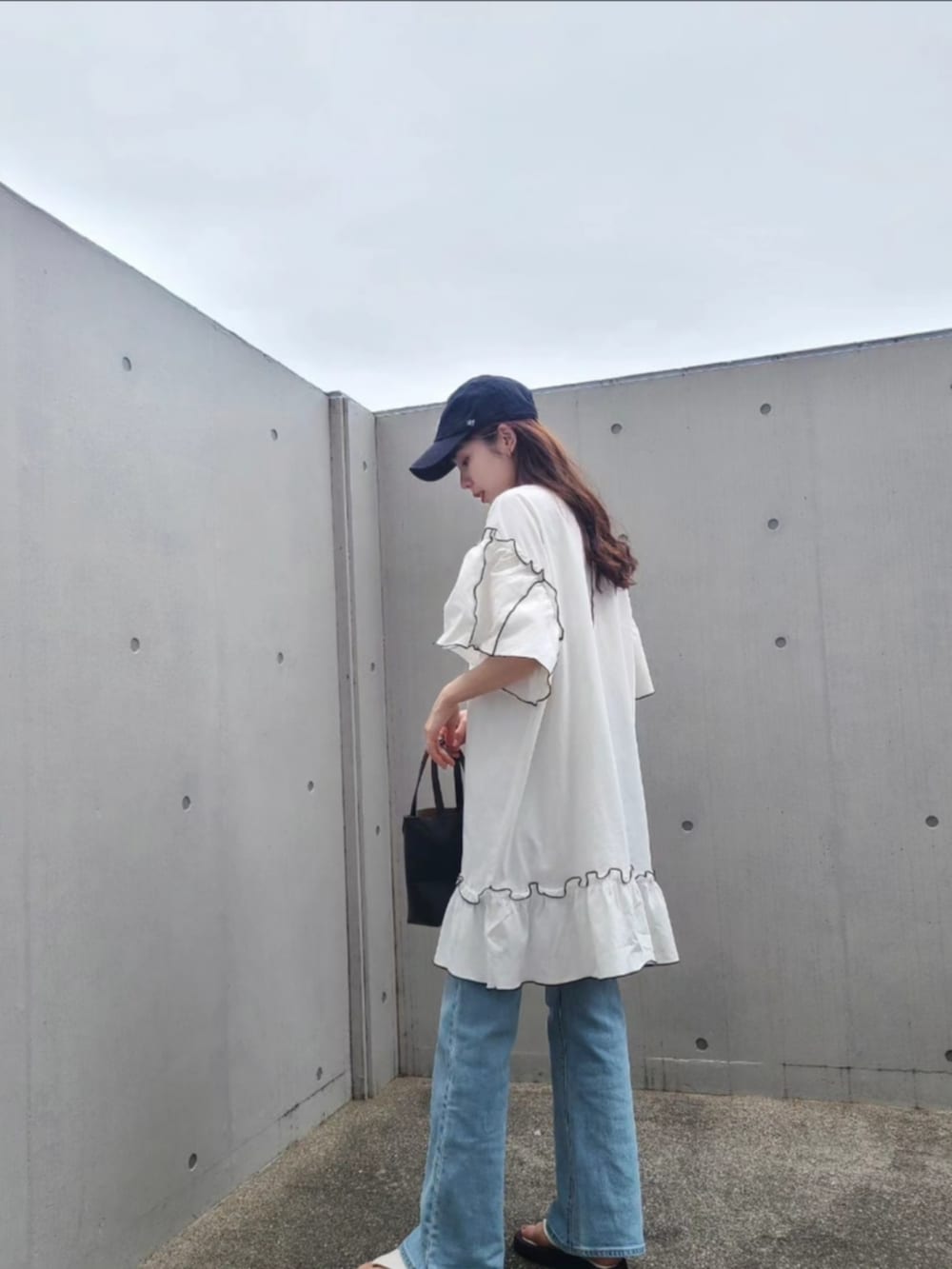 ブラック系のトートバッグ、ブルー系のデニムパンツ、ホワイト系のサンダルを着用したレディースの春コーディネートの3枚目の写真