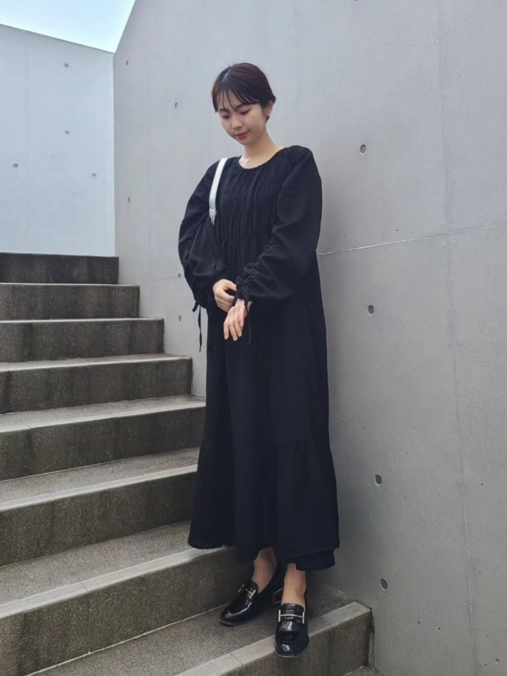 ブラック系のローファー、シルバー系のバッグ、ブラック系のワンピースを着用したレディースの春コーディネートの2枚目の写真