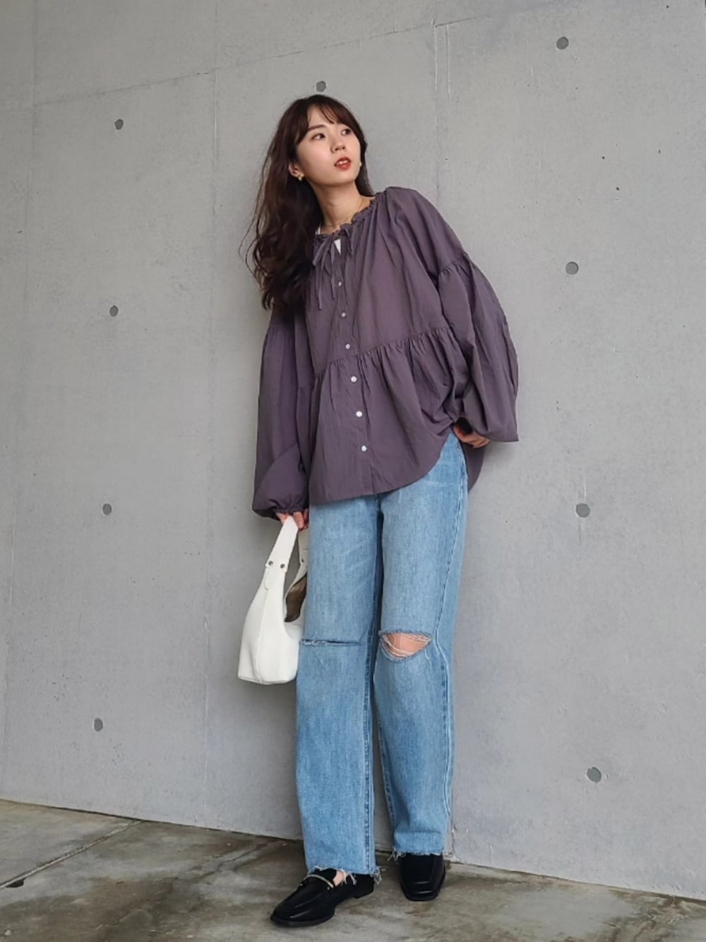 ブルー系のデニムパンツ、ホワイト系のハンドバッグ、ブラウン系のアイシャドウを着用したレディースの春コーディネートの2枚目の写真