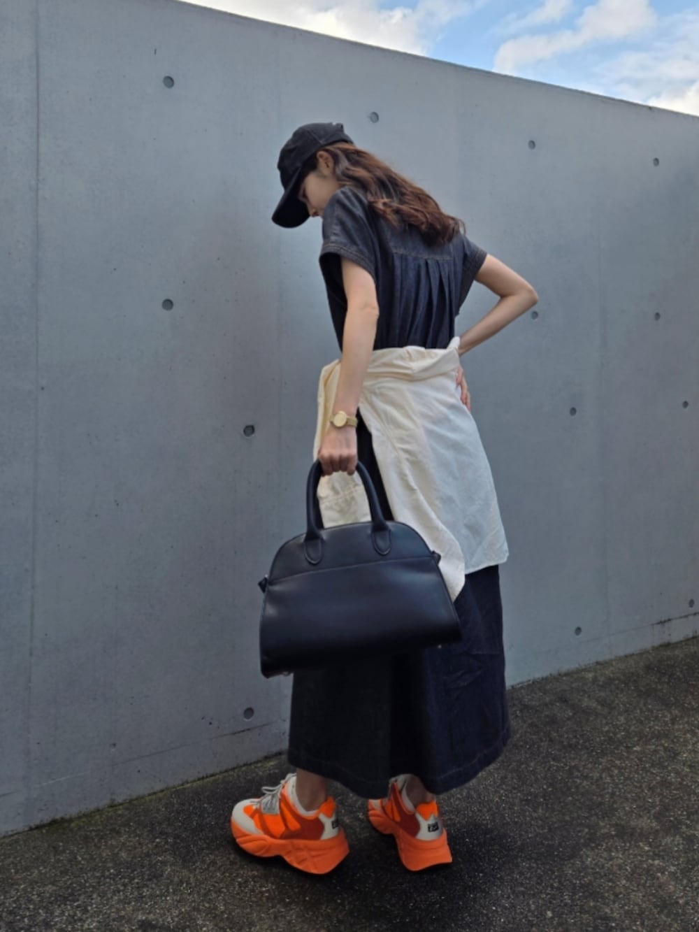 オレンジ系のスニーカー、ブラック系のボストンバッグ、ブラック系のワンピース/ドレスを着用したレディースの春コーディネートの4枚目の写真