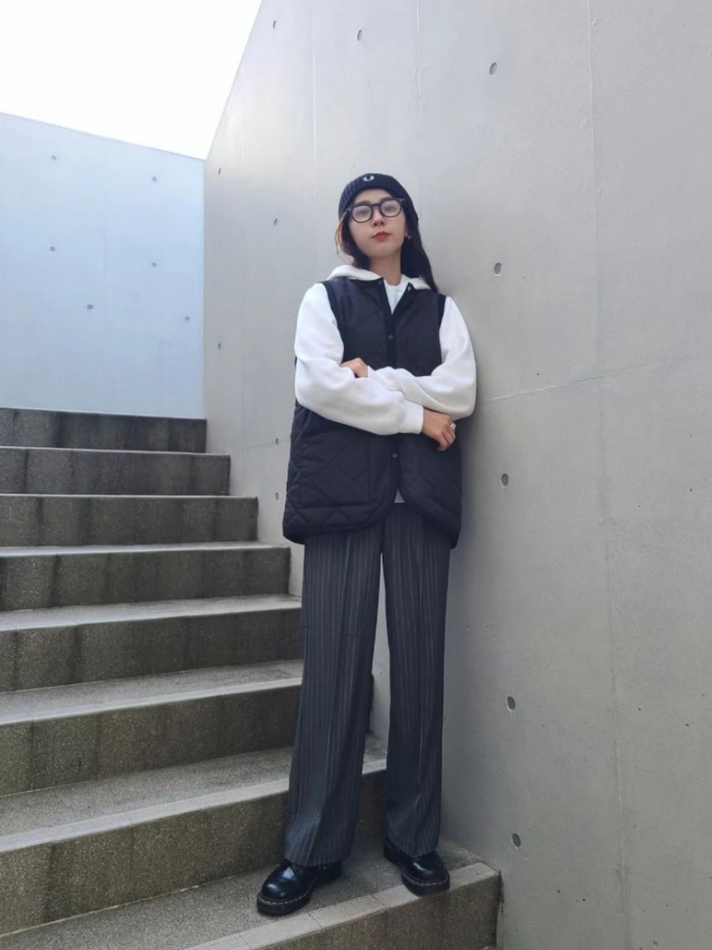 ブラック系のベスト、グレー系のスラックス、ブラック系のブーツを着用したレディースの秋コーディネートの2枚目の写真