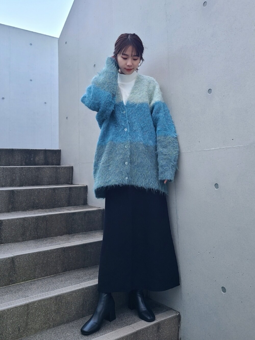ブルー系のカーディガン/ボレロ、ブラック系のブーツを着用したレディースの冬コーディネートの3枚目の写真