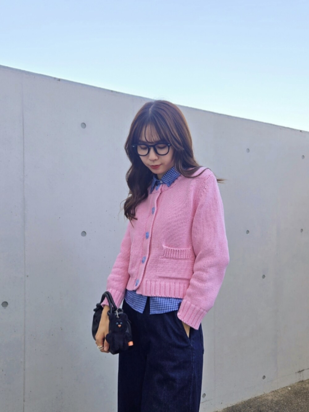 ピンク系のカーディガン/ボレロ、ブルー系のシャツ/ブラウス、ブラック系のハンドバッグを着用したレディースの秋コーディネートの2枚目の写真