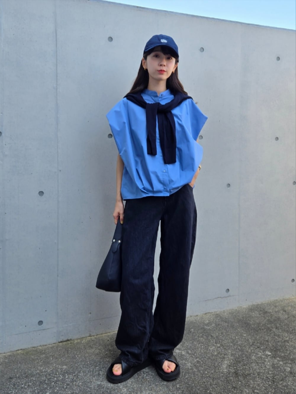 ブラック系のハンドバッグ、ブラック系のデニムパンツ、ブルー系のニット/セーターを着用したレディースの秋コーディネートの3枚目の写真