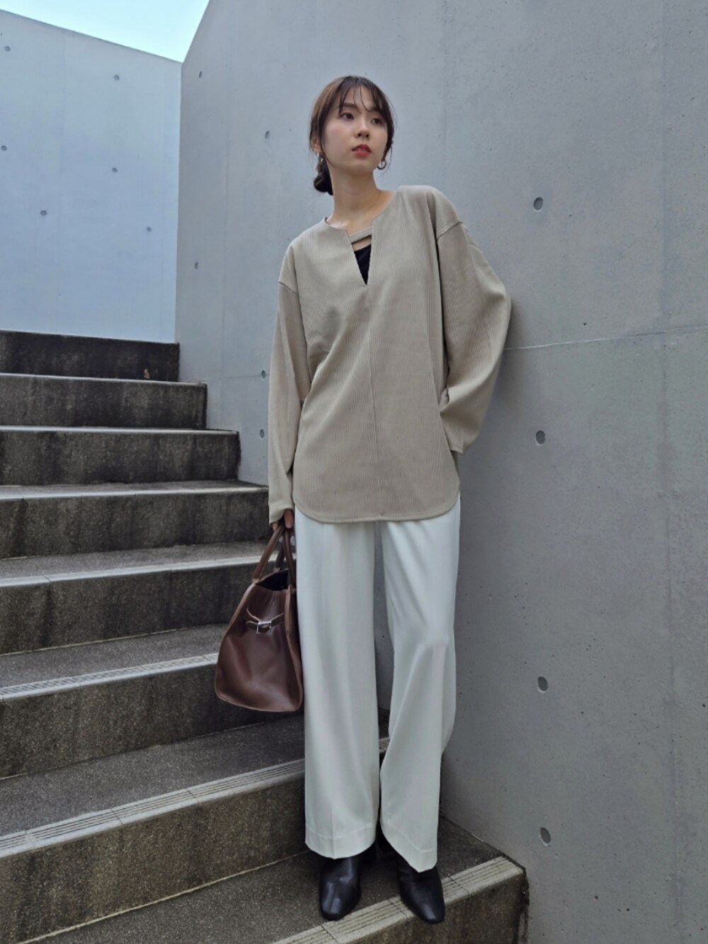 ベージュ系のTシャツ/カットソー、ホワイト系のパンツ、ブラック系のブーツを着用したレディースの秋コーディネートの2枚目の写真