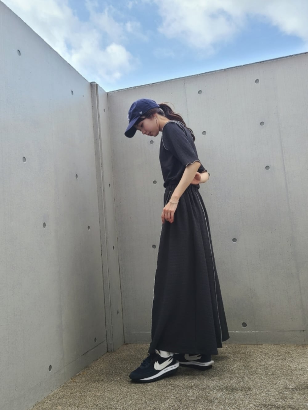 グレー系のTシャツ/カットソー、グレー系のスカート、ブルー系のスニーカーを着用したレディースの春コーディネートの2枚目の写真