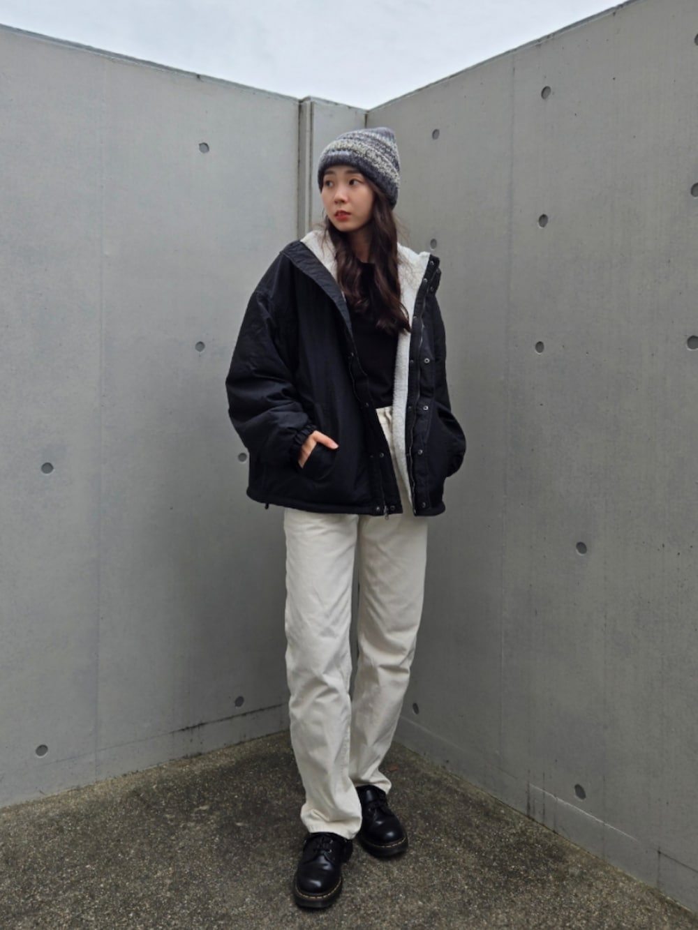 ブラック系のブルゾン、ホワイト系のデニムパンツ、ブラック系のブーツを着用したレディースの秋コーディネートの3枚目の写真