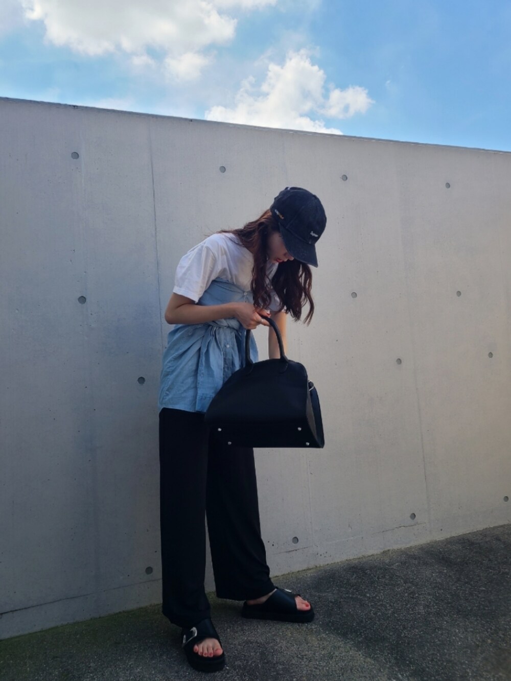 ブラック系のサンダル、ブラック系のボストンバッグ、ブラック系のパンツを着用したレディースの夏コーディネートの2枚目の写真