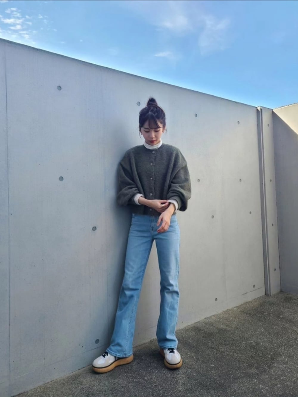 グリーン系のカーディガン/ボレロ、ブルー系のデニムパンツ、ホワイト系のスニーカーを着用したレディースの秋コーディネートの2枚目の写真