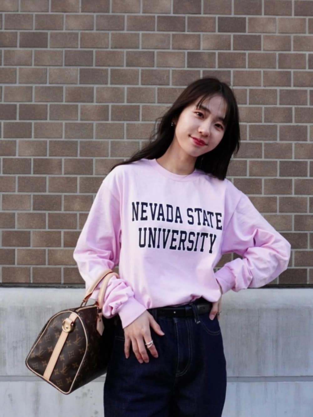 ブラウン系のスニーカー、ブルー系のデニムパンツ、ピンク系のTシャツ/カットソーを着用したレディースの冬コーディネートの3枚目の写真