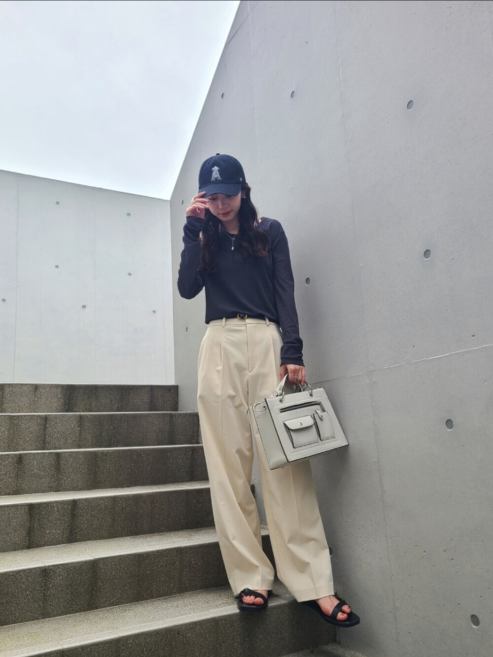 ホワイト系のバッグ、ホワイト系のパンツ、ブラック系のサンダルを着用したレディースの夏コーディネートの2枚目の写真