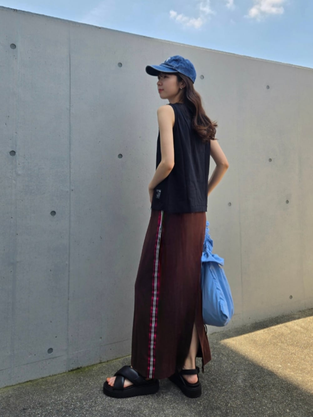 ブラウン系のスカート、ブラック系のサンダル、ブルー系のショルダーバッグを着用したレディースの夏コーディネートの3枚目の写真