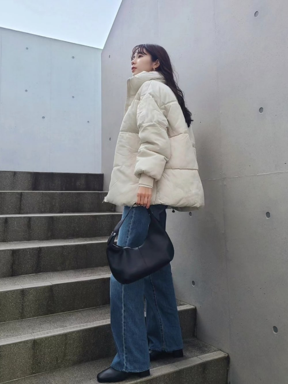 ホワイト系のダウンジャケット/コート、ブラック系のブーツ、ブラック系のハンドバッグを着用したレディースの冬コーディネートの2枚目の写真