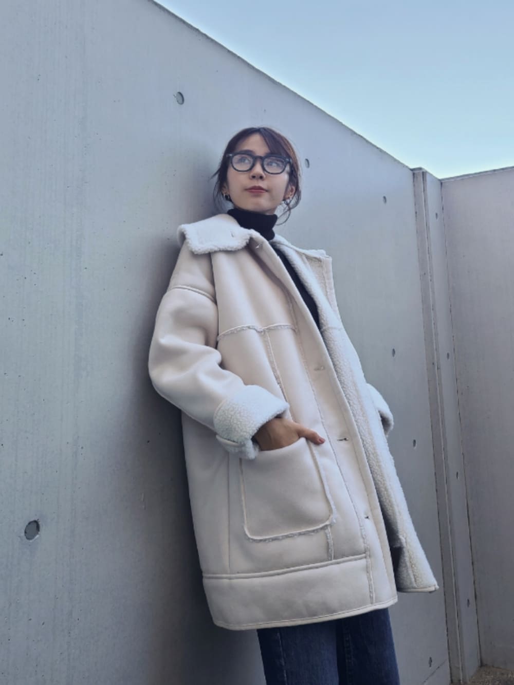 ブルー系のデニムパンツ、ブラック系のブーツ、ホワイト系のムートンコートを着用したレディースの秋コーディネートの4枚目の写真