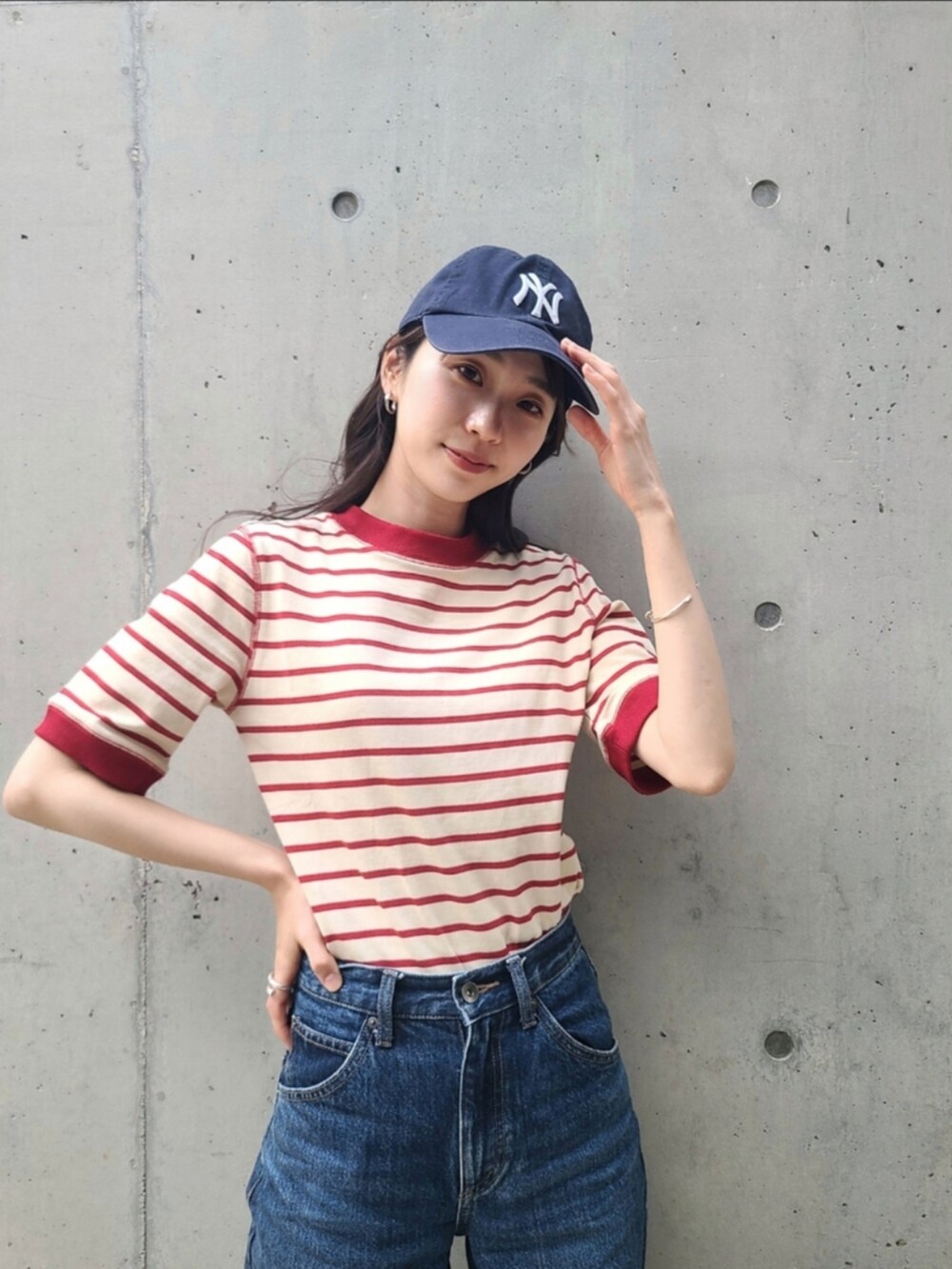 レッド系のTシャツ/カットソー、ブルー系のデニムパンツ、ブルー系のスニーカーを着用したレディースの春コーディネートの2枚目の写真