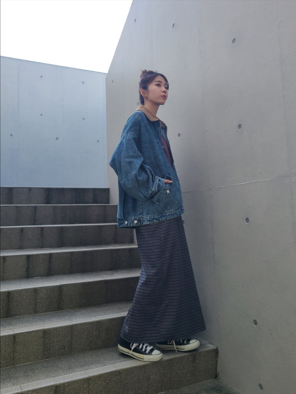 レッド系のTシャツ/カットソー、ブルー系のデニムジャケット、ブルー系のスカートを着用したレディースの秋コーディネートの3枚目の写真