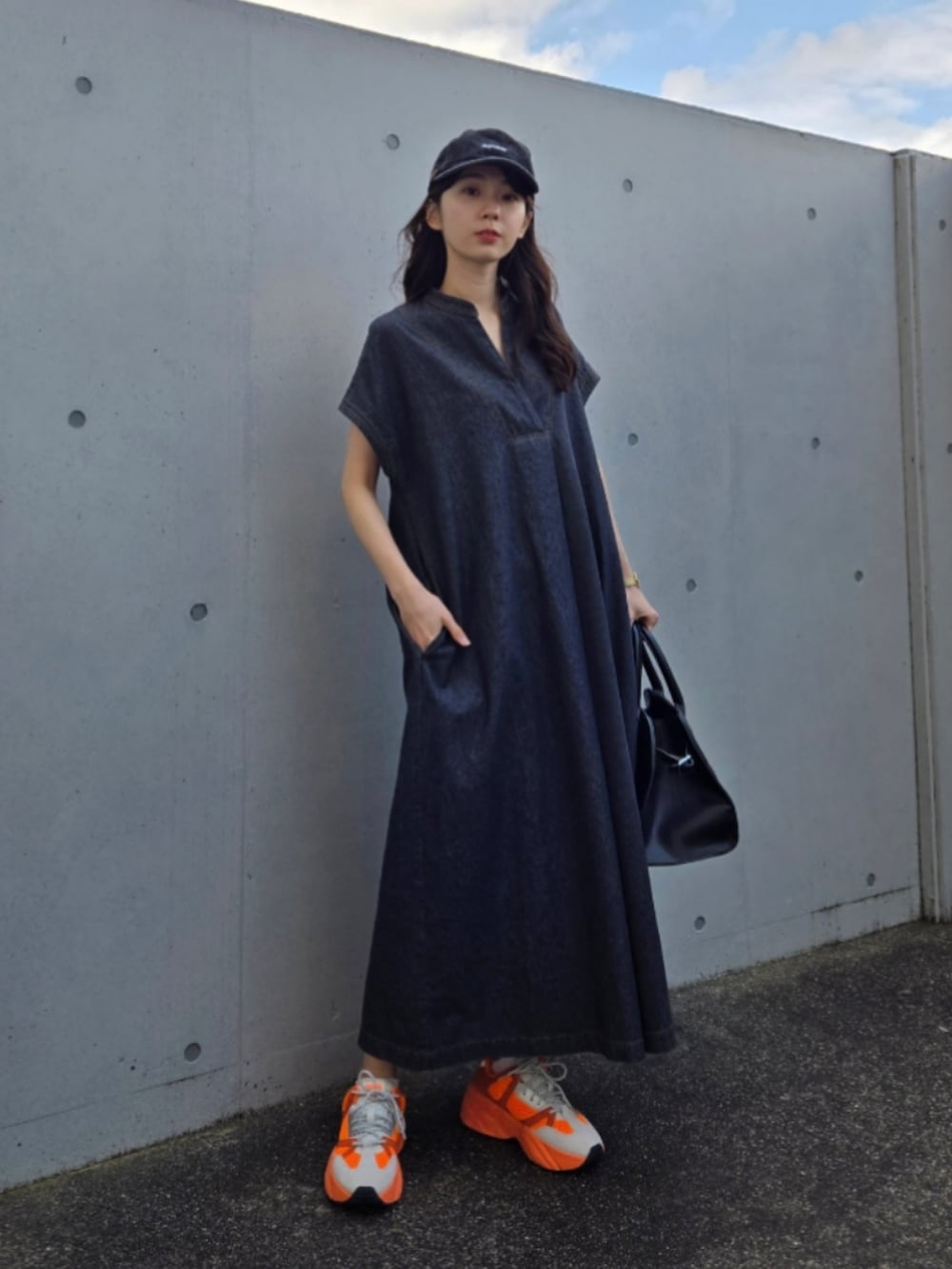 オレンジ系のスニーカー、ブラック系のボストンバッグ、ブラック系のワンピース/ドレスを着用したレディースの春コーディネートの3枚目の写真