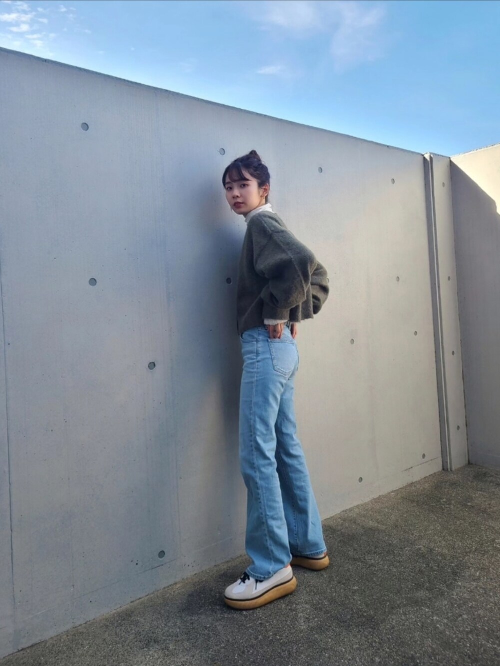 グリーン系のカーディガン/ボレロ、ブルー系のデニムパンツ、ホワイト系のスニーカーを着用したレディースの秋コーディネートの3枚目の写真