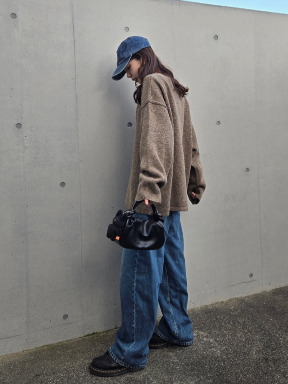 ブルー系のデニムパンツ、ブラウン系のカーディガン/ボレロ、ブラック系のハンドバッグを着用したレディースの秋コーディネートの2枚目の写真