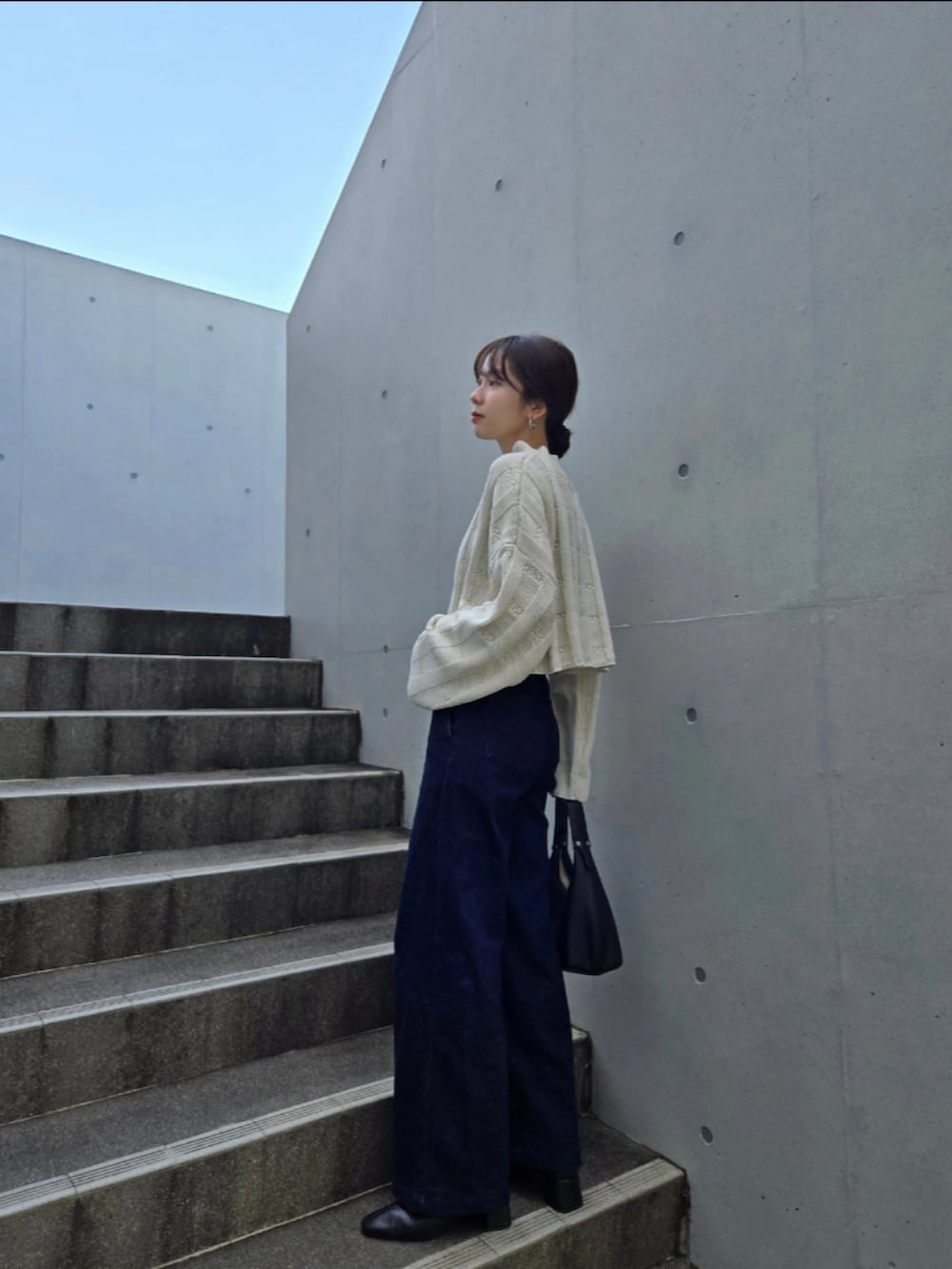 ホワイト系のニット/セーター、ブルー系のデニムパンツ、ブラック系のブーツを着用したレディースの秋コーディネートの3枚目の写真